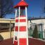 Lighthouse single playhouse with climbing net in outdoor setting