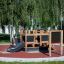 Playground structure Blackboard 156 cm with slide and climbing elements in a park setting.