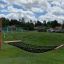 Triple Hammock in a playground set against a grassy field and houses in the background