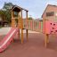 Inclusive playground equipment Epsilon with a slide, climbing wall, and bridge.