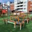 Wooden Balance Course playground equipment on artificial grass in an urban area.