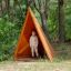 Child standing inside Tipi Nature wooden house on playground in forest setting