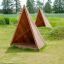 Tipi Nature wooden house playground shelter made of natural wood on grassy field.
