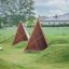 Tipi Nature wooden house playground equipment made of natural wood on grassy field.
