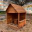 Wooden playhouse with table and stool set in an outdoor setting.