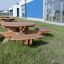 Round table & benches in a grassy outdoor area near a modern building.