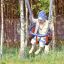Child enjoying a Wooden Baby double swing in a leafy playground