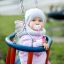 Child sitting in Wooden Baby double swing outdoors