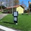 Gas Pump interactive playground equipment on artificial grass near a slide.
