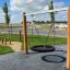 Wooden Double Swing Robinia (BNS 90) in a playground with a tire seat.