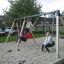 Children playing on a 1+2 multiple swing in a playground.