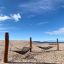 Double Hammock on a sandy beach with wooden supports and a clear blue sky.