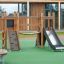 Mini Play II playhouse for children with wooden climbing wall and slide on playground.