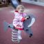 A child playing on a Walrus rocking spring rider in a playground.