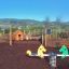 Double Pony rocking playground equipment in a park setting with mountains in the background.