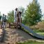 Children playing on Wooden Stair playground equipment with a slide outdoors.
