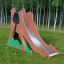Camel single slide play equipment with a metal slide in a grassy area with trees in the background.