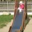A child going down the Camel single slide in a playground.