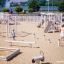 Children playing on Balance playground equipment in a sandy play area.