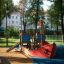 Small Ship sandbox in outdoor playground with trees and buildings in the background.