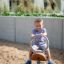 Boy riding a Bike rocking playground equipment in a sandbox.