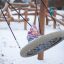 Child playing on the Single Swing in a snowy playground.