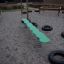 Balance board for children on playground with gravel and tire obstacles.