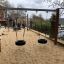 Double swing set on a sandy playground.