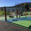 Wooden Double swing set on colorful playground with padded flooring.