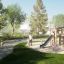 Children playing on Alstad Eco playground set in a park with green trees and grass.