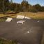 Skate park with Curb Horizontal ramps and obstacles set up on asphalt surface.