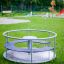 Playground Merry-Go-Round on a grassy field with park background.