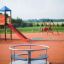 Merry-Go-Round playground equipment on an outdoor play area with slide and swings in the background