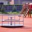 Merry-Go-Round play equipment on a playground with orange surface.