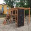 Climbing Kiosk Nature playground structure with wooden frame, climbing nets, and rock wall in a sand