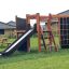 Outdoor wooden play structure Climbing Kiosk Nature with slide, ladder, and climbing net in backyard