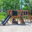 Children playing on Romping Center Nature playground structure with slides and climbing features out
