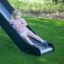 Child sliding down the Challenger Nature slide in a grassy outdoor playground.