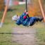 Child riding on a Medium Cableway playground equipment in a park.