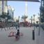 Children playing on a red Double Seesaw in a modern urban playground.