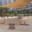 Double Seesaw in a modern urban playground with a shade sail overhead.