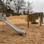 Stainless steel Slide in a sandy outdoor playground by the lake.