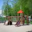 Playground featuring a wooden climbing structure with slides and a red roof next to a Powerclimber c