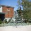 Powerclimber climbing net on sandy playground in front of building.