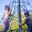 Two children climbing on Powerclimber climbing net outdoors.