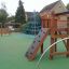 Powerclimber climbing net on a playground with a slide and swing set