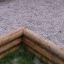 Corner of Palisade Horizontal (running meter) wooden logs setup in a gravel area