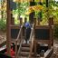A child playing on a Small Ship Nature playground structure in an autumn forest.