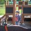 Child playing on the Small Ship Nature outdoor playground equipment.