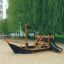Wooden playground structure shaped like a Small Ship Nature with a slide and climbing frame.